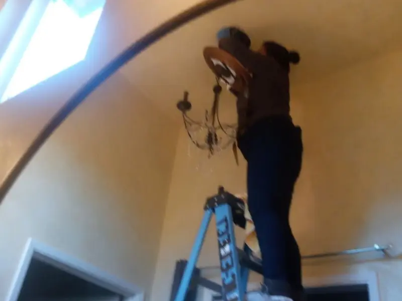 Electrician installing a chandelier in a Galt residence